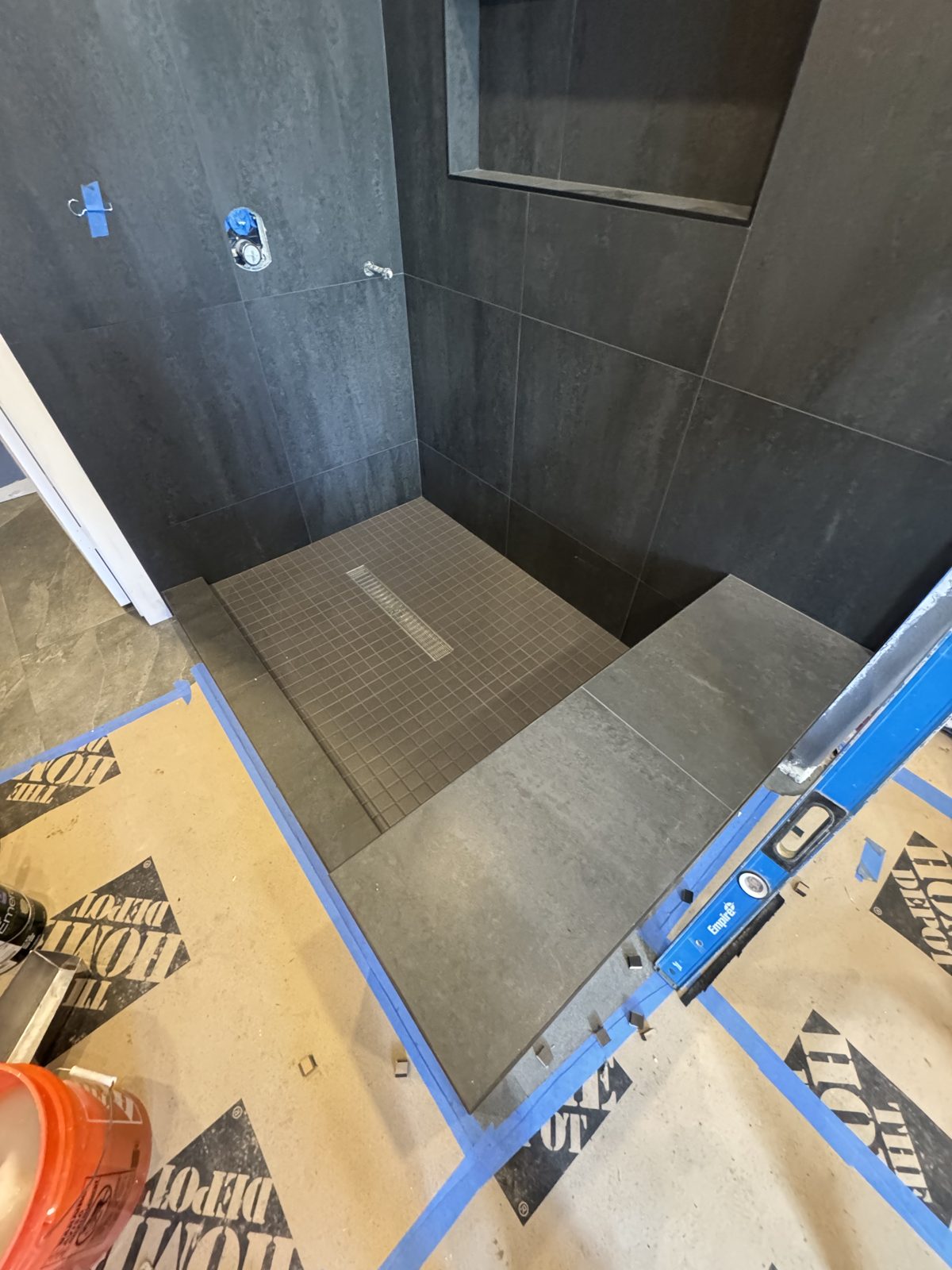 Shower waterproofing membrane and large-format dark tile being installed