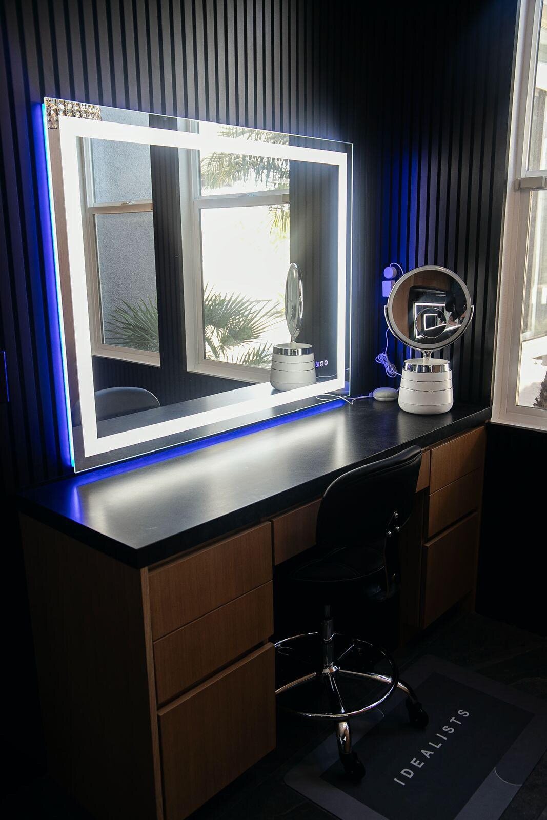 Backlit makeup vanity station with fluted black wall paneling