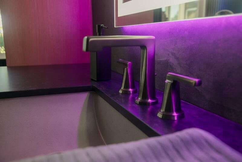 Brushed-nickel widespread faucet on a honed slate vanity with accent lighting