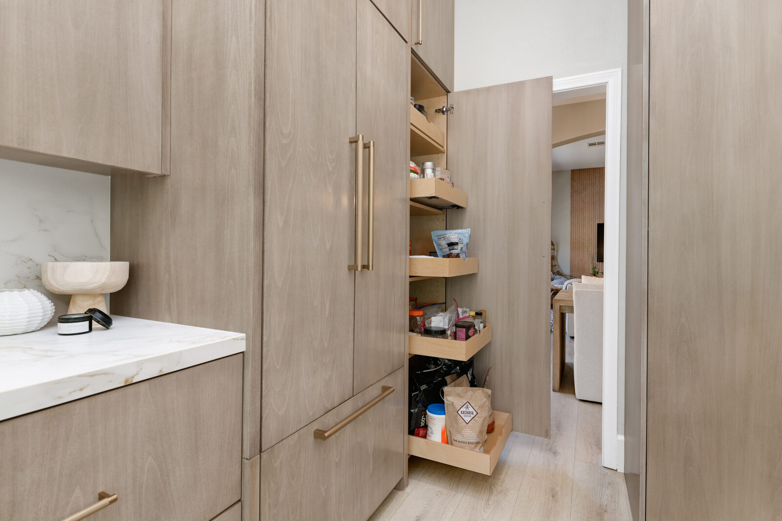 Custom full-extension pantry pull-out shelving inside white-oak cabinetry
