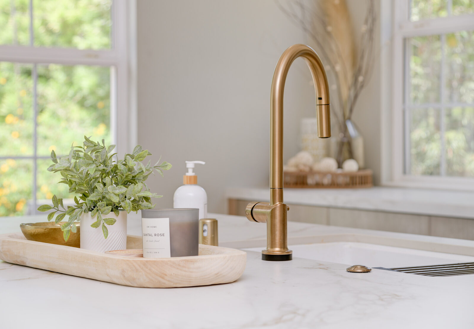 Brushed-brass gooseneck kitchen faucet on a marble-look quartz countertop