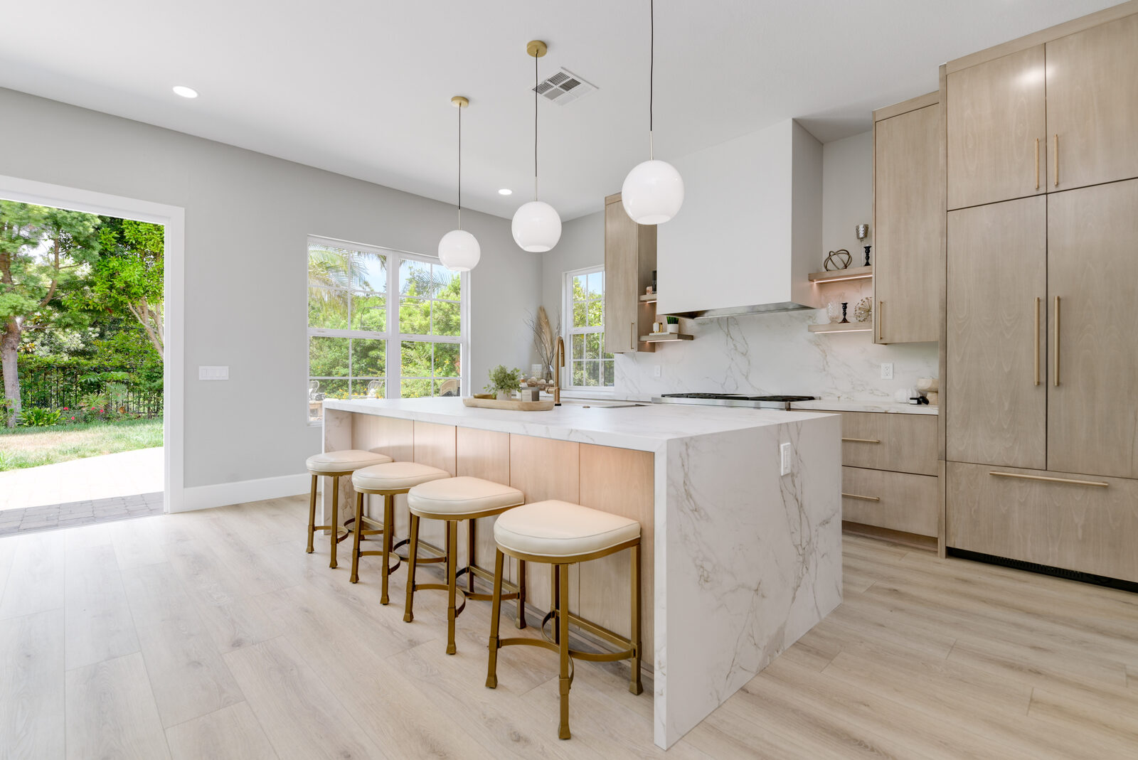 Modern white-oak kitchen remodel with a waterfall Calacatta quartz island and brushed-brass fixtures by IL Total Design & Build in Carlsbad, CA